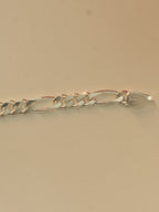 Close view of the stamped end tab on the figaro chain bracelet.