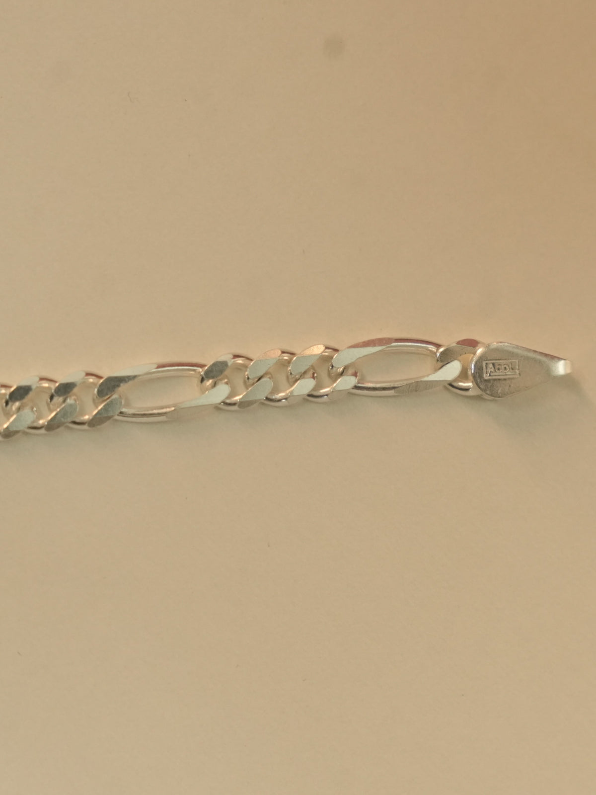 Close view of the stamped end tab on the figaro chain bracelet.