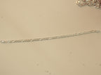 The figaro chain bracelet laid out straight, showing its full length.