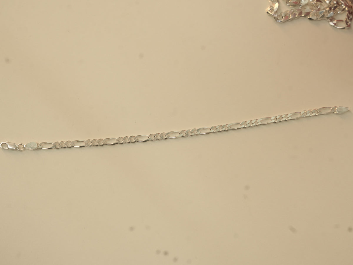 The figaro chain bracelet laid out straight, showing its full length.