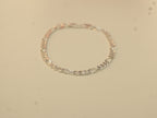 The silver figaro chain bracelet laid in a circle.