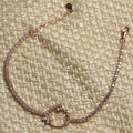 Rose gold-tone sterling silver bracelet set with cubic zirconia, its open wreath centre resting on woven fabric.