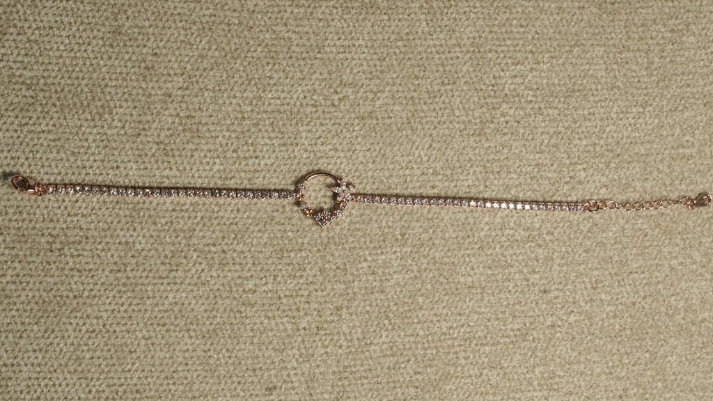 Full length of the rose gold-tone cubic zirconia bracelet laid straight with its wreath motif at the centre.