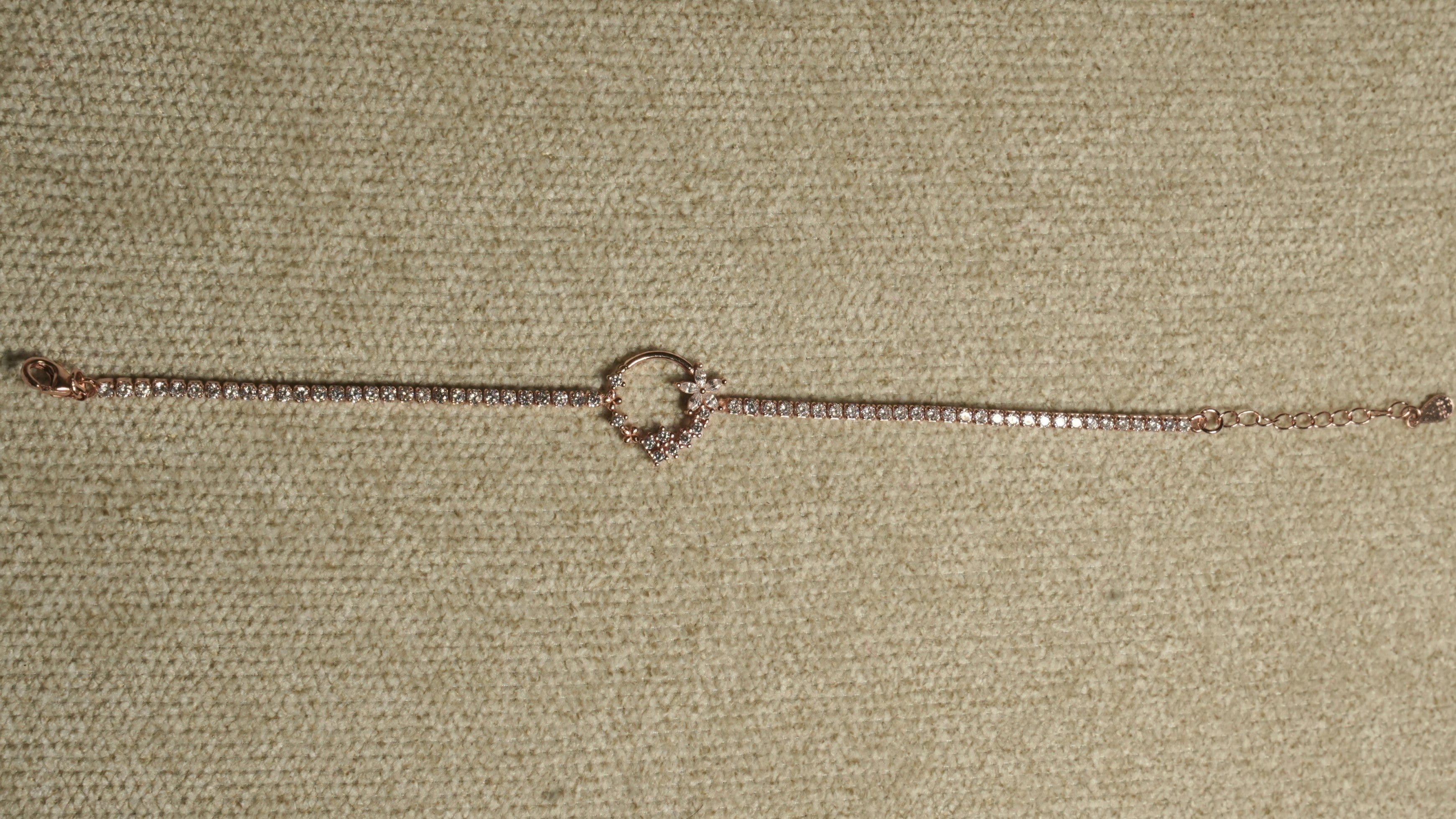 Full length of the rose gold-tone cubic zirconia bracelet laid straight with its wreath motif at the centre.