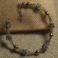 Multi-strand textured silver bracelet stationed with fluted silver beads and hammered rose gold-tone beads, with extender chain, resting on a jute pouch.