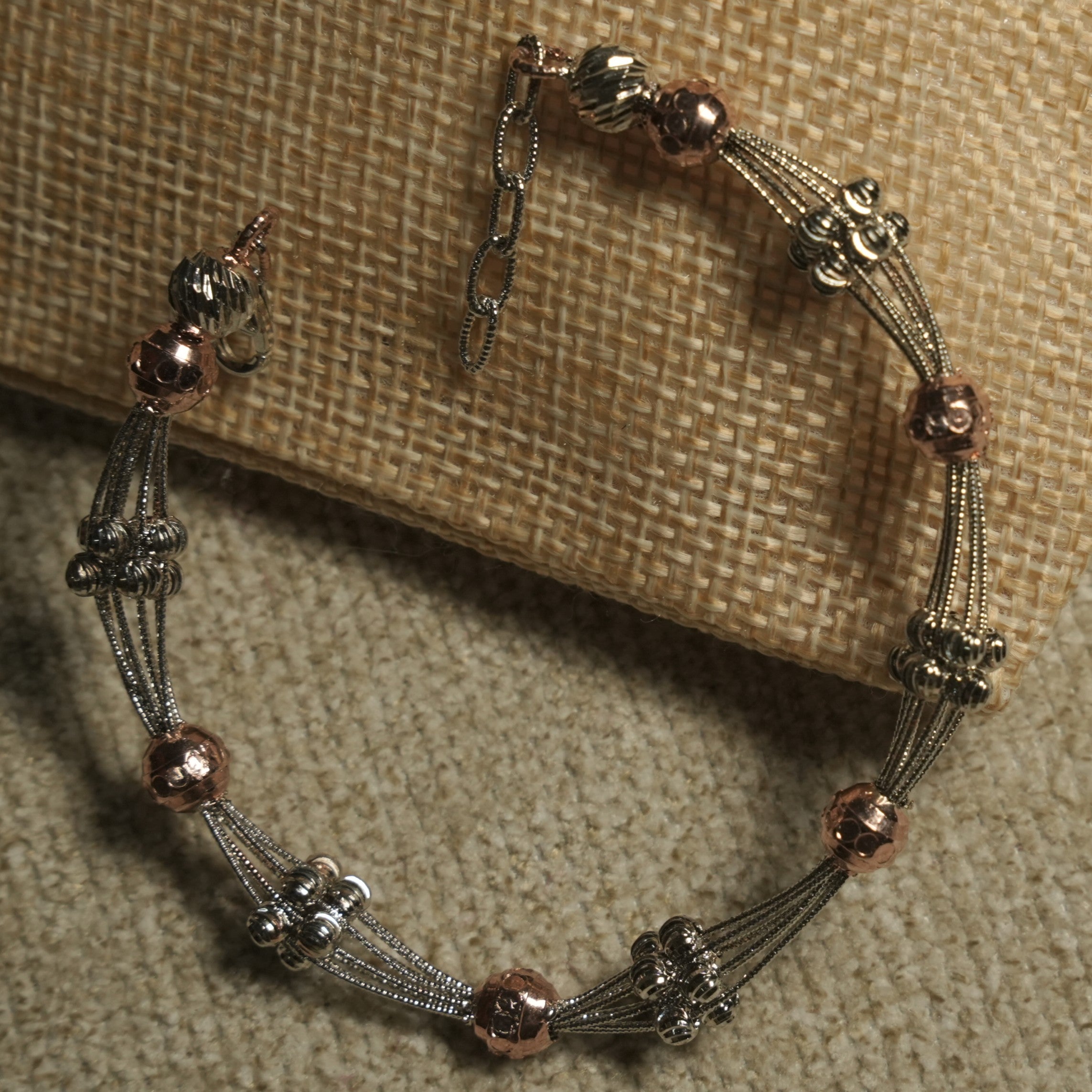 Overhead view of the two-tone beaded bracelet showing grouped fluted silver beads, rose gold-tone orbs and its extender chain.