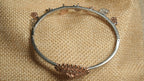 Back view of the charm bangle showing its hinge, hook closure and the reverse of the rose gold-tone teardrop cluster.