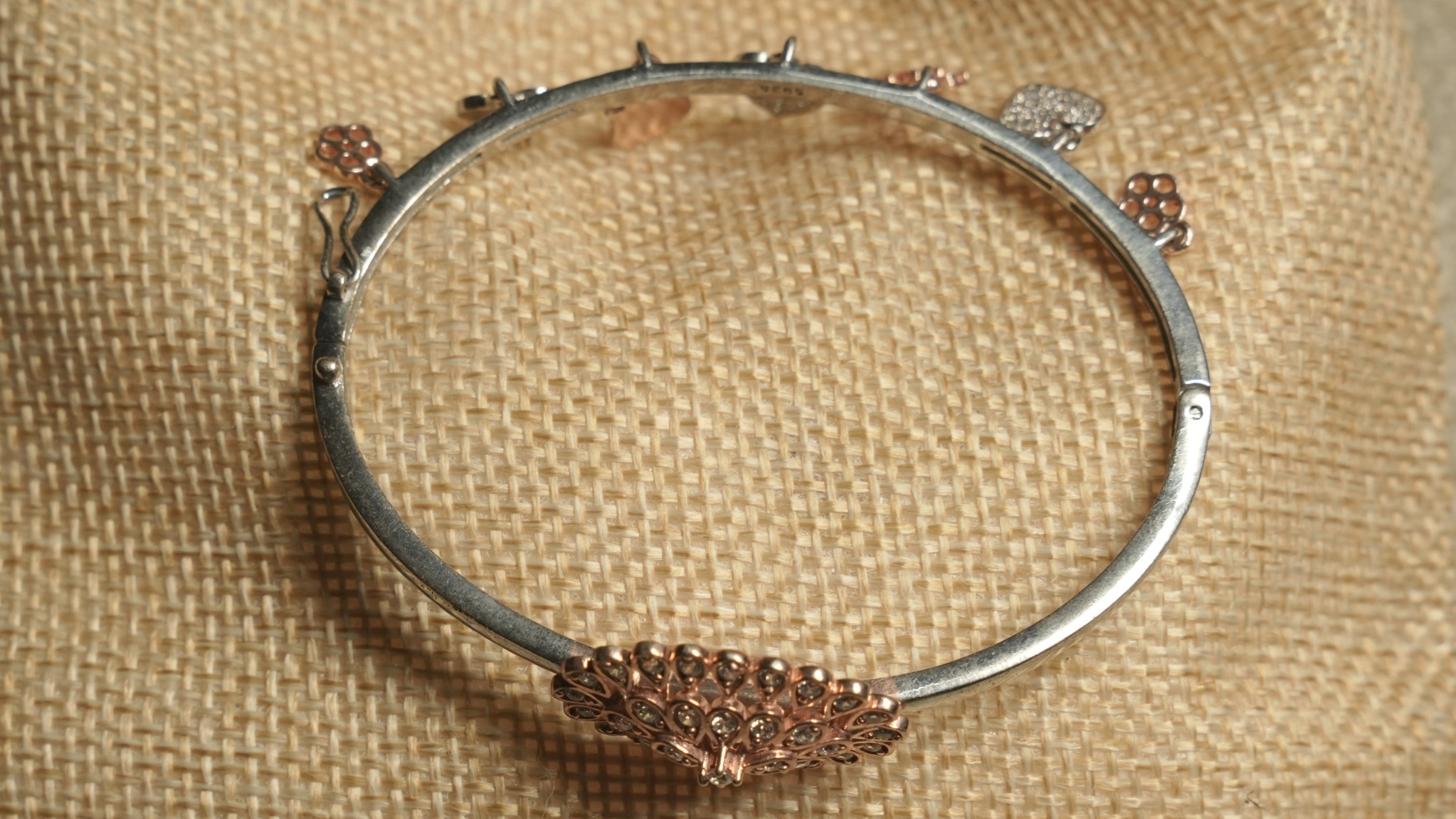 Back view of the charm bangle showing its hinge, hook closure and the reverse of the rose gold-tone teardrop cluster.