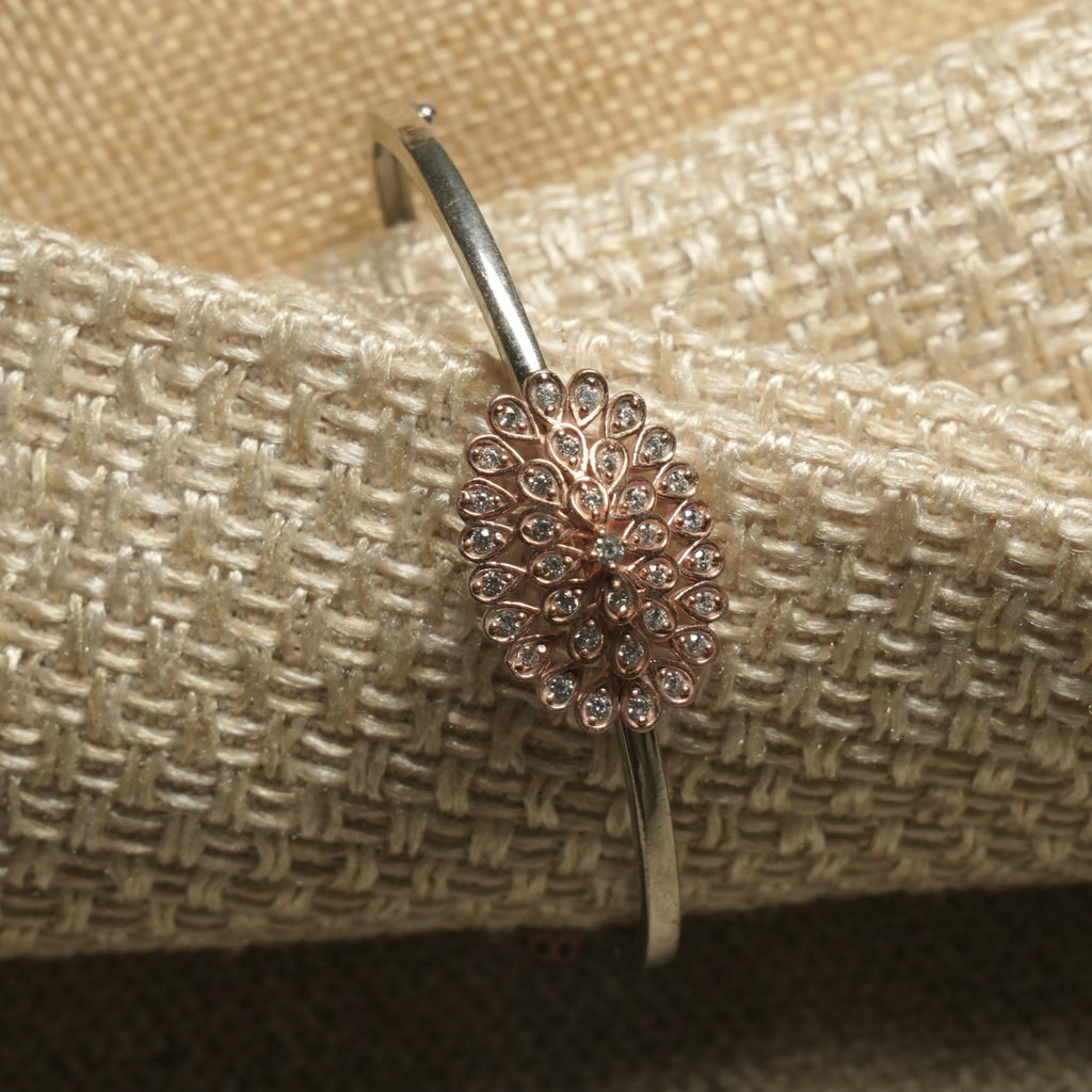 Close view of the fanned rose gold-tone teardrop cluster set with cubic zirconia on the slim silver band.