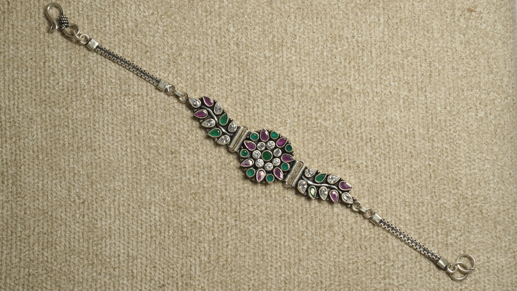 Oxidised sterling silver bracelet with a round floral cluster of white cubic zirconia and green and pink stones, leaf-set side panels, box chaiMG and an S-hook clasp.