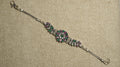 Oxidised sterling silver bracelet with a round floral cluster of white cubic zirconia and green and pink stones, leaf-set side panels, box chaiMG and an S-hook clasp.