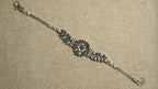 Oxidised sterling silver bracelet with a round floral cluster of white cubic zirconia and green and pink stones, leaf-set side panels, box chaiMG and an S-hook clasp.