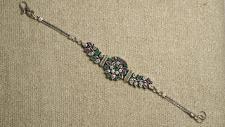 Oxidised sterling silver bracelet with a round floral cluster of white cubic zirconia and green and pink stones, leaf-set side panels, box chaiMG and an S-hook clasp.