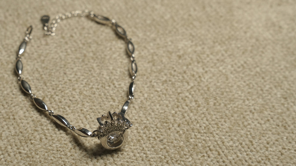 Overhead view of the full crown motif bracelet showing its slim marquise links, clasp and extender chain.