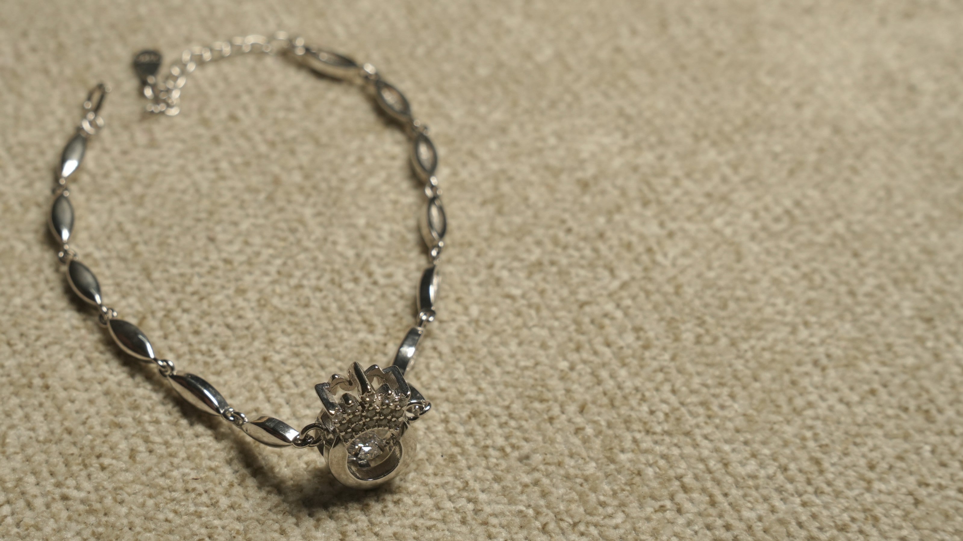 Overhead view of the full crown motif bracelet showing its slim marquise links, clasp and extender chain.