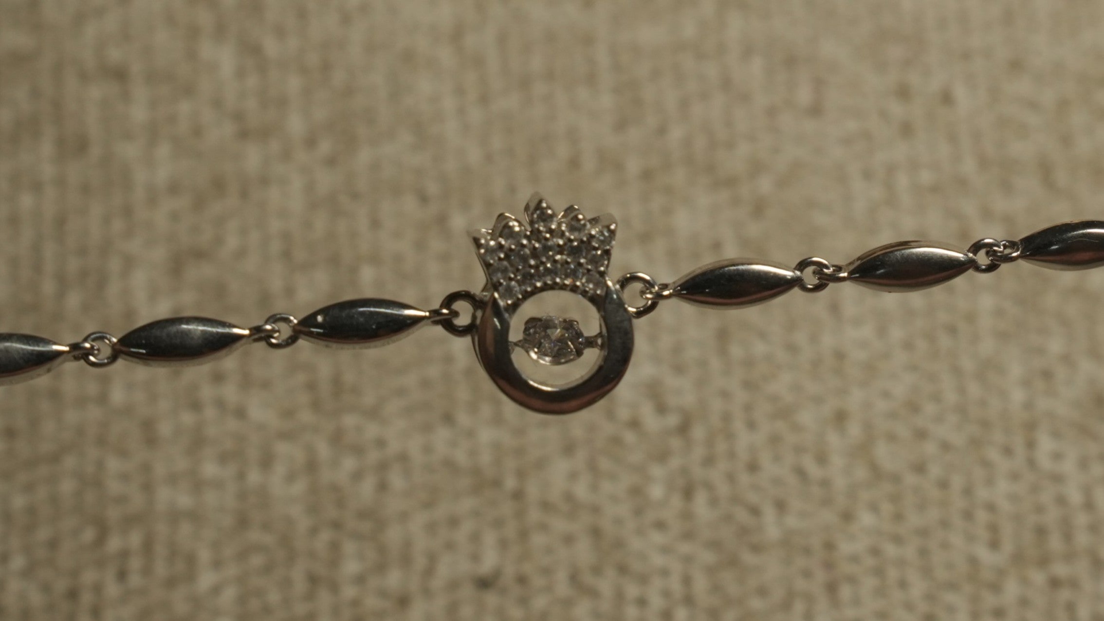 Close view of the Bejewelled crown and open circle motif with its free-moving cubic zirconia along the chain.