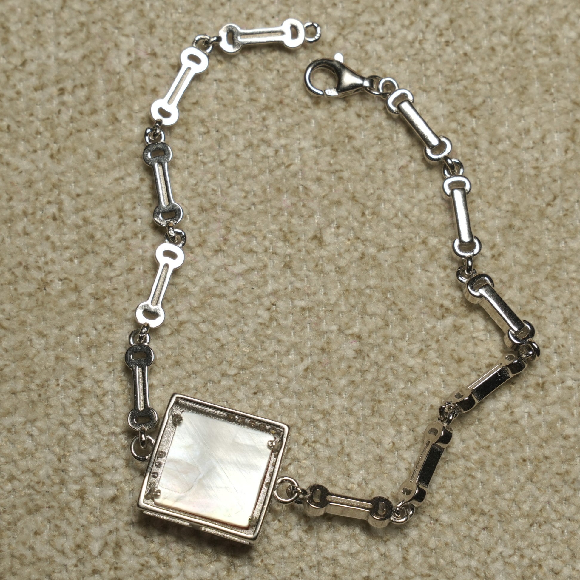 Reverse of the bracelet showing the shell-backed panel, open bar links and lobster clasp.
