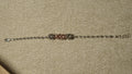 Slim sterling silver bracelet of faceted beads with three fluted bead clusters, the centre one rose gold-tone, laid out straight on beige fabric.