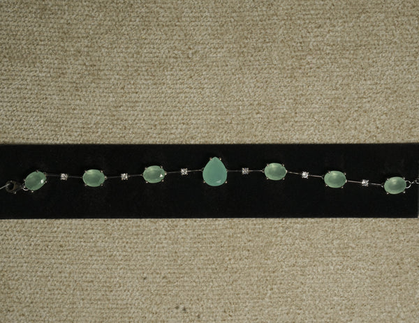 Sterling silver bracelet of prong-set sea-green oval stones with a pear-shaped centre stone, spaced by round cubic zirconia, displayed on black velvet.