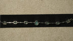 Reverse of the green stone bracelet showing its prong settings, slim bar links and lobster clasp on black velvet.