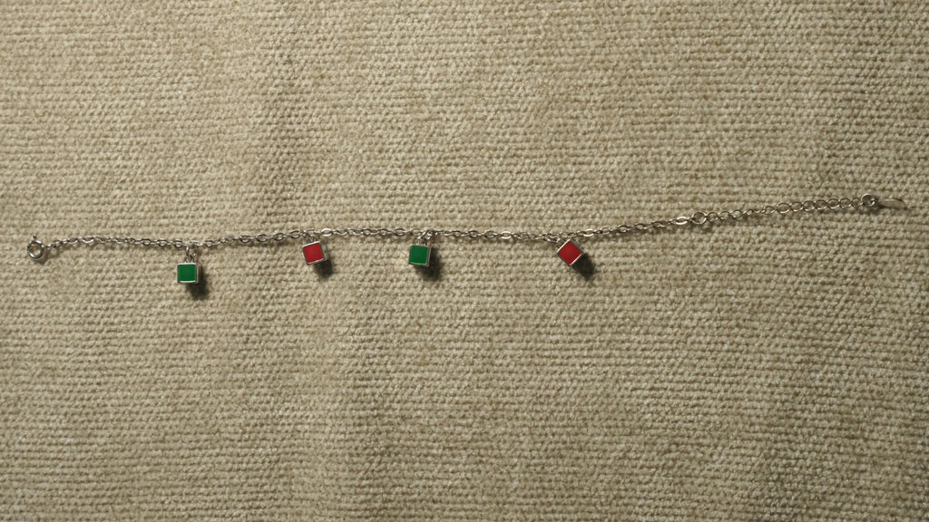 The enamel square bracelet laid out straight, showing its four coloured squares, chain and extender.