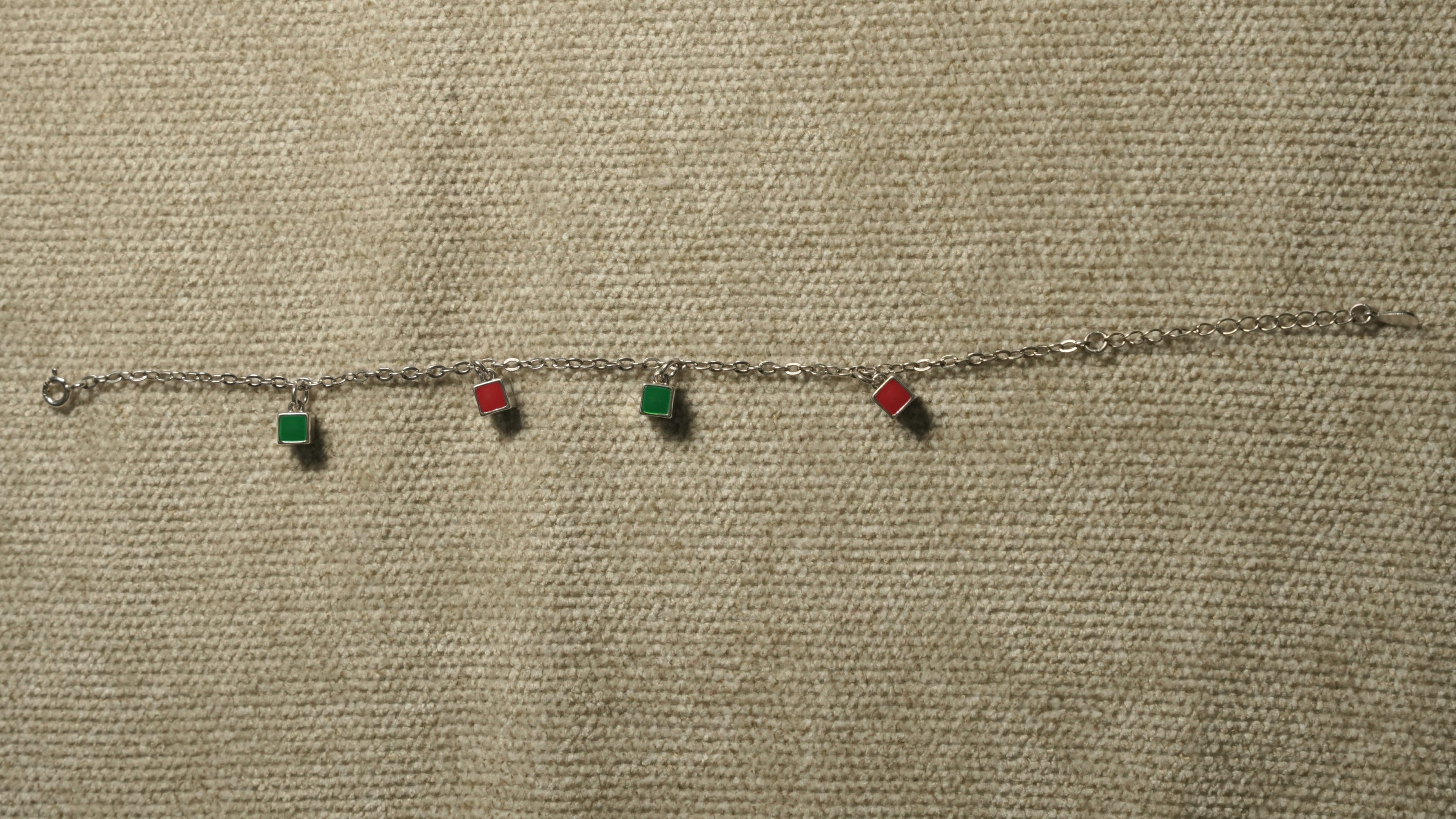 The enamel square bracelet laid out straight, showing its four coloured squares, chain and extender.
