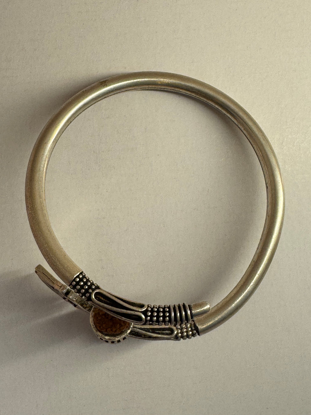 Reverse of the sterling silver kada on a pale ground, showing the open round band and the overlap of the two ends.