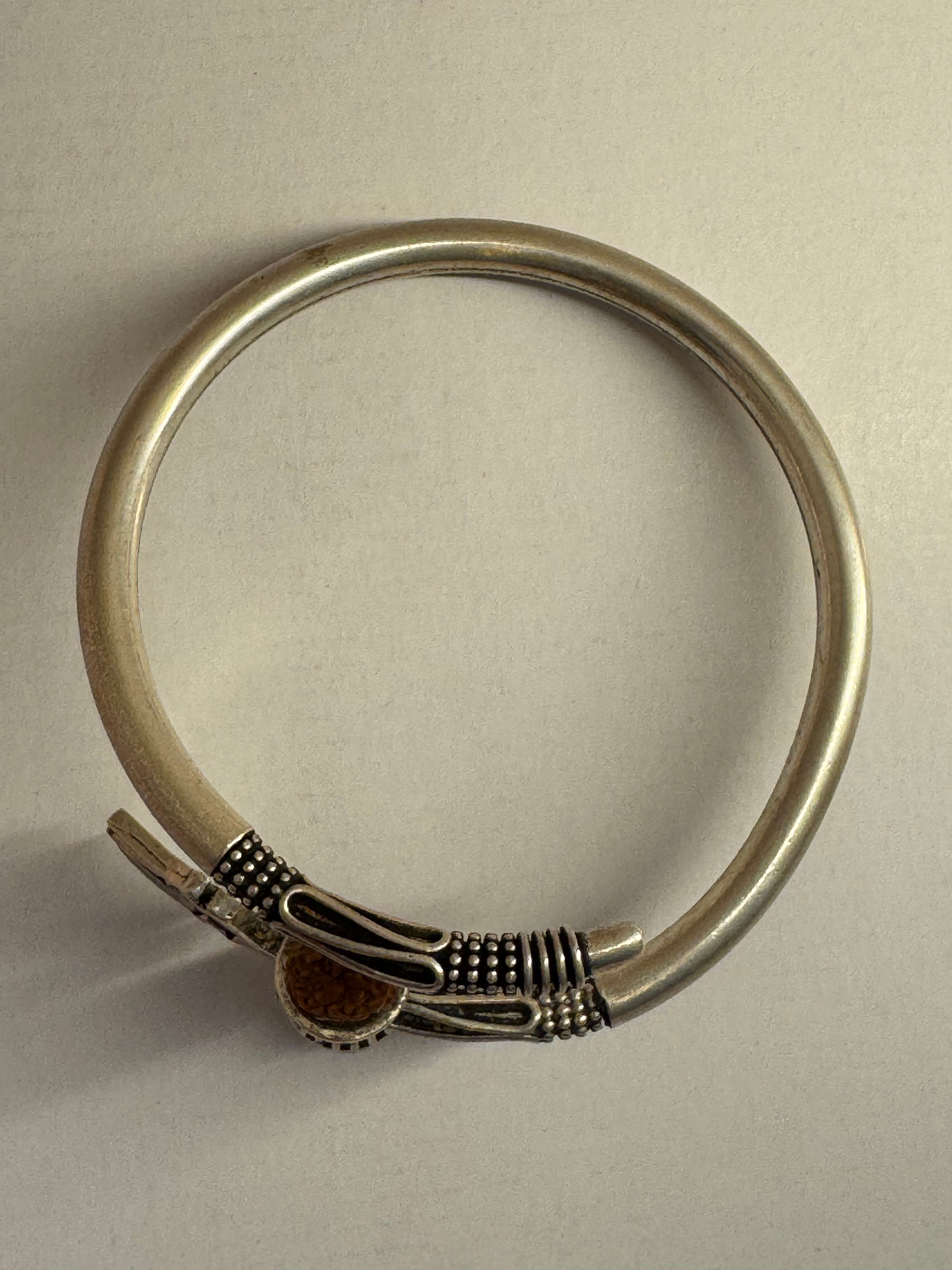 Reverse of the sterling silver kada on a pale ground, showing the open round band and the overlap of the two ends.
