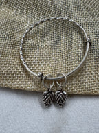 Twisted sterling silver bangle on jute cloth, with two oxidised leaf drops hanging at the opening.