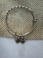 Sterling silver adjustable bangle laid flat across jute and cream cloth, showing the rope twist along the band.