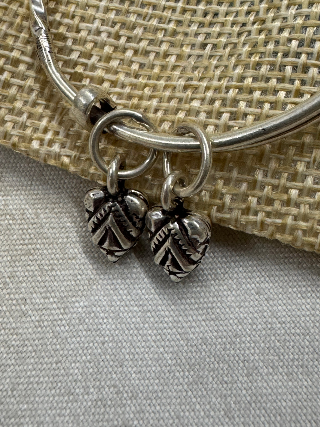 Close view of the two oxidised leaf drops and their jump rings on the sterling silver bangle.