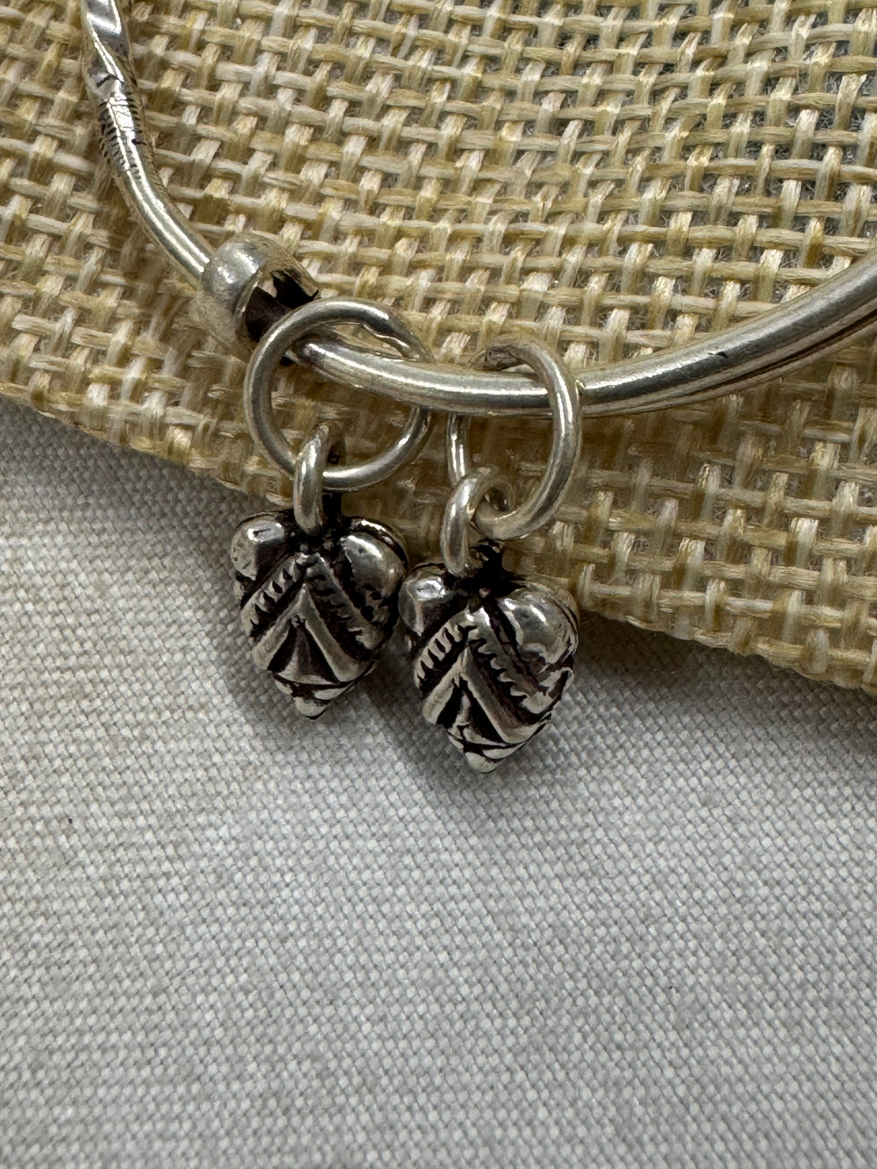 Close view of the two oxidised leaf drops and their jump rings on the sterling silver bangle.