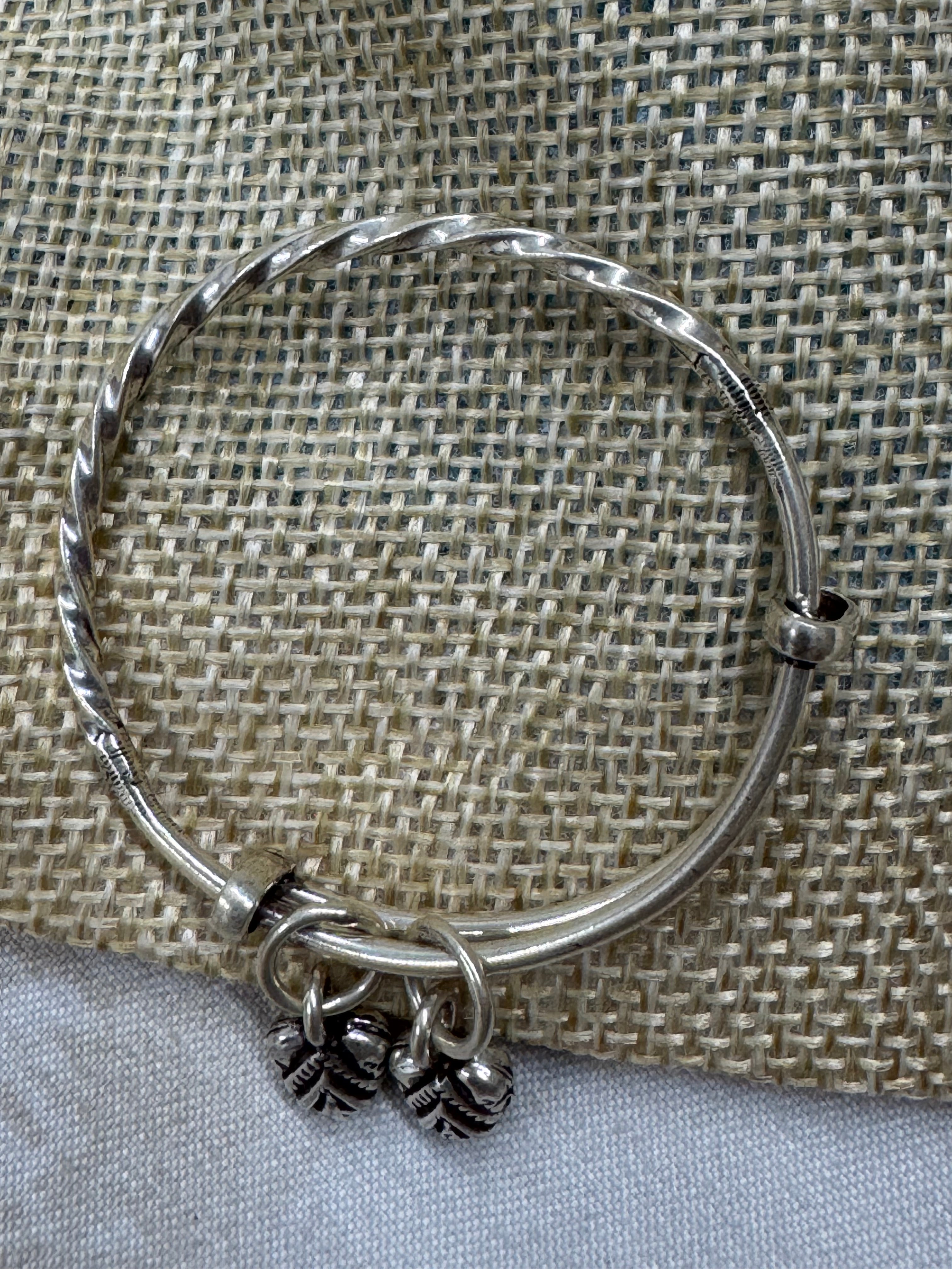 Sterling silver bangle on jute, showing the sliding ends and the bead stoppers that hold the size.