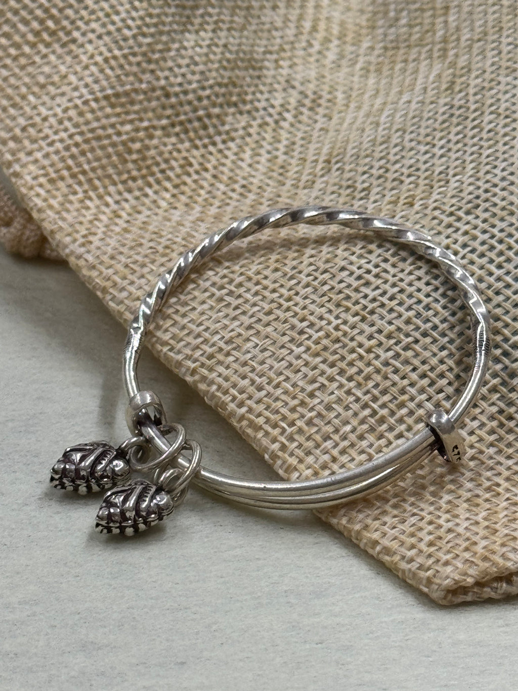 Close view of the sterling silver bangle showing the 925 stamp on the collar beside the leaf drops.