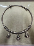 Sterling silver bangle laid flat on paper, showing the coiled front half and the plain sliding ends.