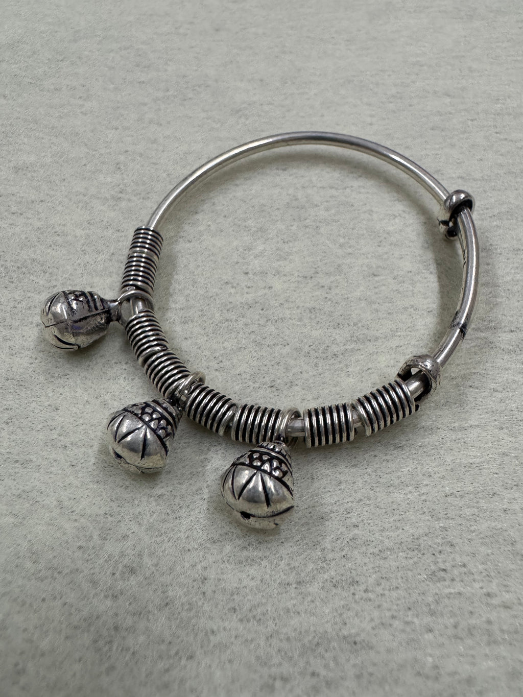 Overhead view of the sterling silver bangle with its three ghungroo bells hanging clear of the band.
