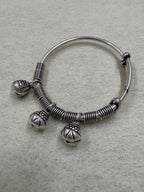 Overhead view of the sterling silver bangle with its three ghungroo bells hanging clear of the band.