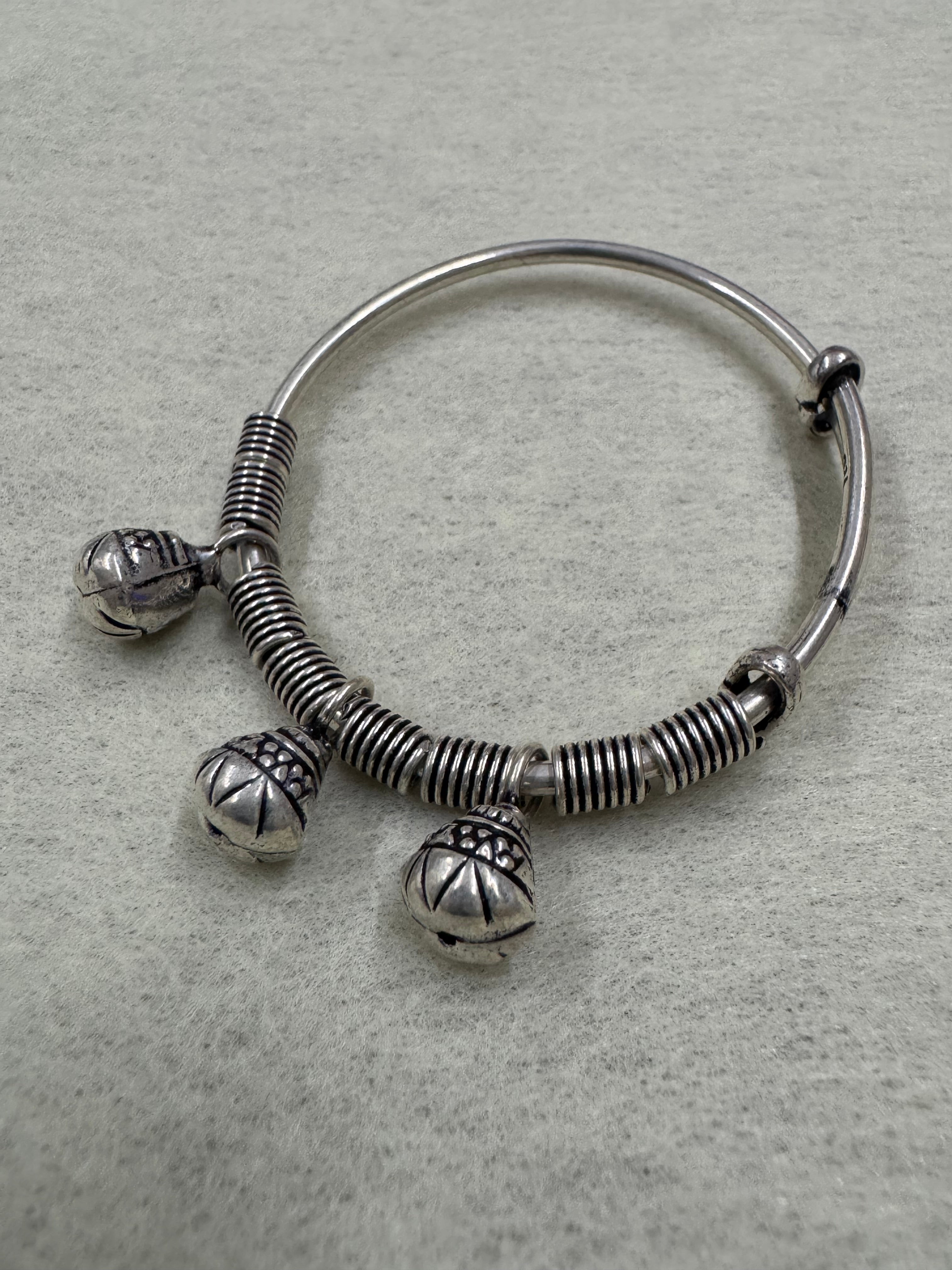 Overhead view of the sterling silver bangle with its three ghungroo bells hanging clear of the band.