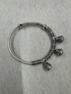 Sterling silver adjustable bangle on a pale ground, showing the bell slits and the 925 stamp on the plain band.