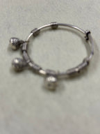 Soft-focus overhead view of the sterling silver bangle showing the coiled sections and the three bells.