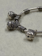 Close view of the ghungroo bells and their jump rings set between the coiled wire blocks on the sterling silver bangle.