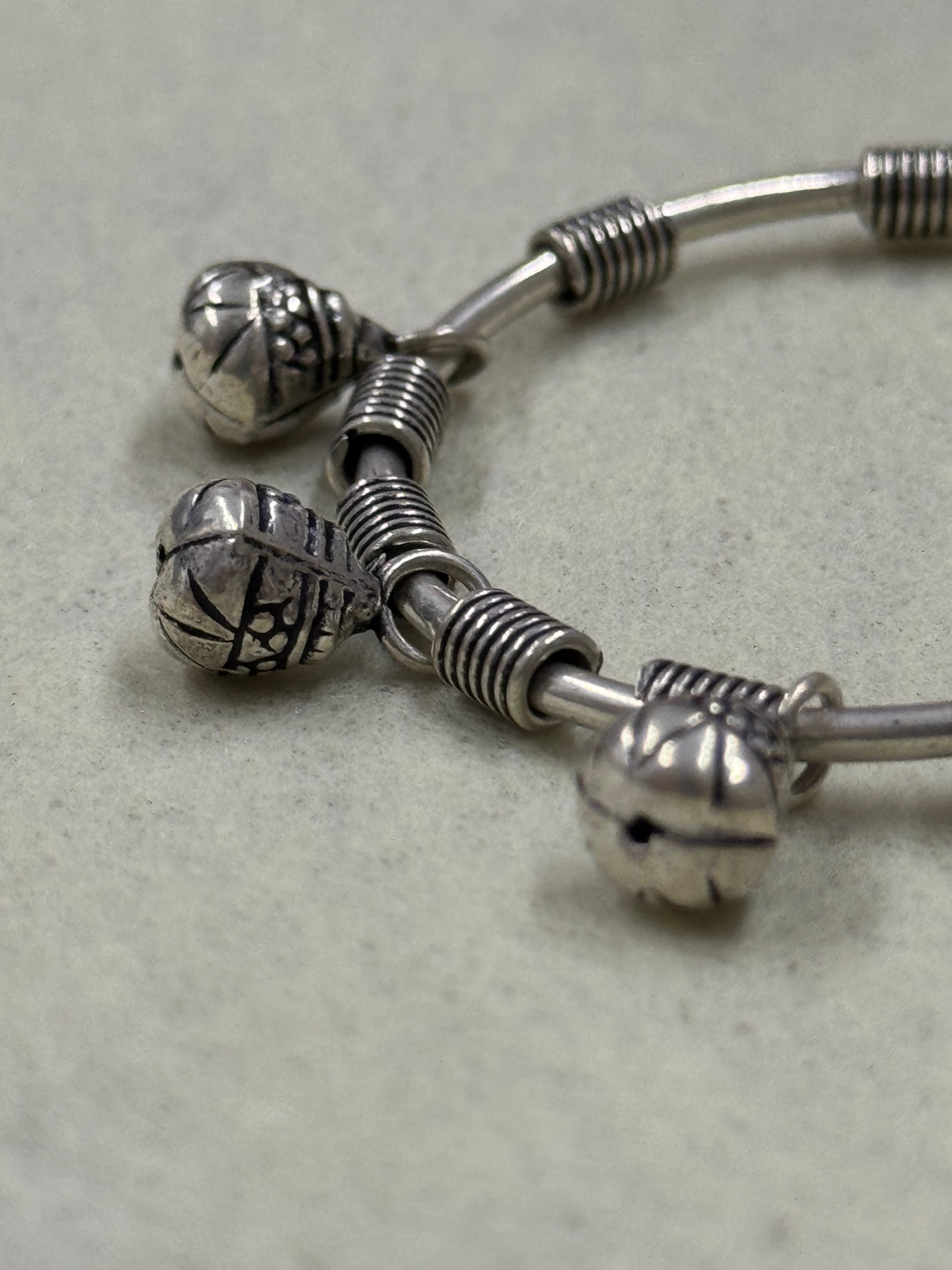 Close view of the ghungroo bells and their jump rings set between the coiled wire blocks on the sterling silver bangle.