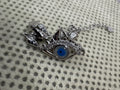 Close view of the sterling silver nazar eye centrepiece with cubic zirconia along the lower lid, on spotted cream knit.