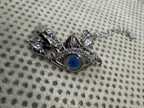 Close view of the sterling silver nazar eye centrepiece with cubic zirconia along the lower lid, on spotted cream knit.