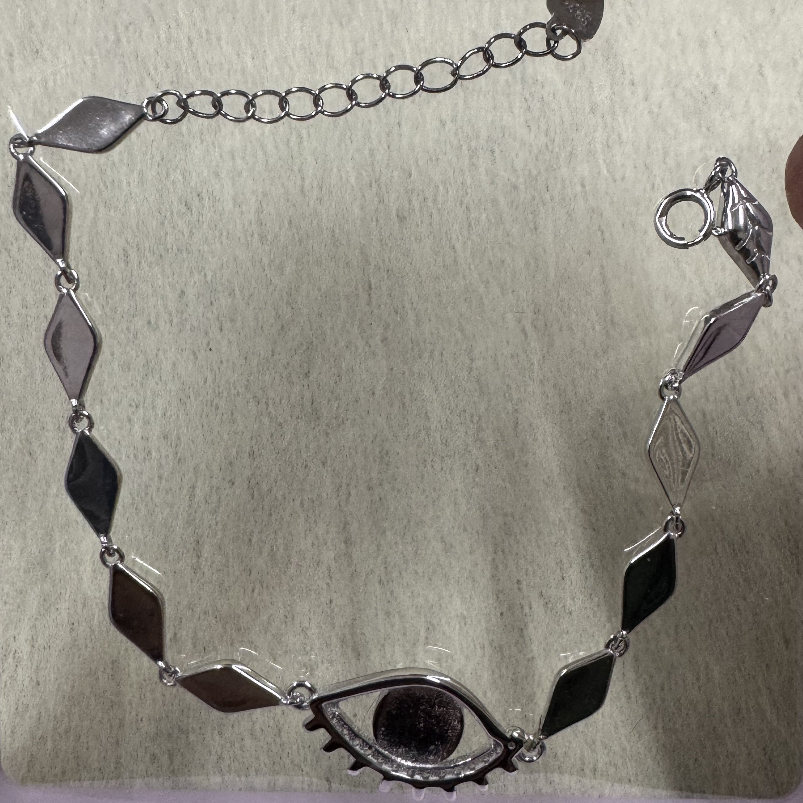 Low-light view of the sterling silver nazar bracelet showing the full run of marquise links and the extender chain.