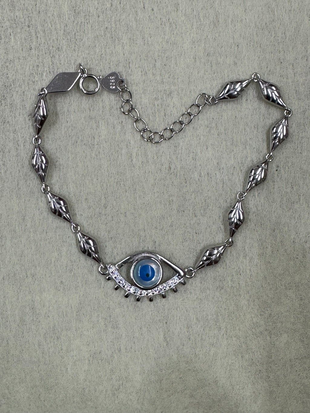 Overhead view of the sterling silver nazar bracelet, with the heart tag stamped 925 at the end of the extender chain.