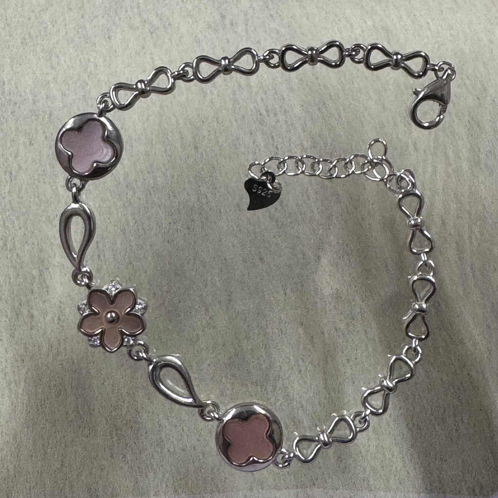 Sterling silver bracelet with two pink quatrefoil discs, a pink flower set with cubic zirconia, and a bow-link chain with lobster clasp.