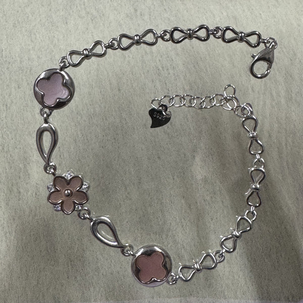 Sterling silver bracelet with two pink quatrefoil discs, a pink flower set with cubic zirconia, and a bow-link chain with lobster clasp.