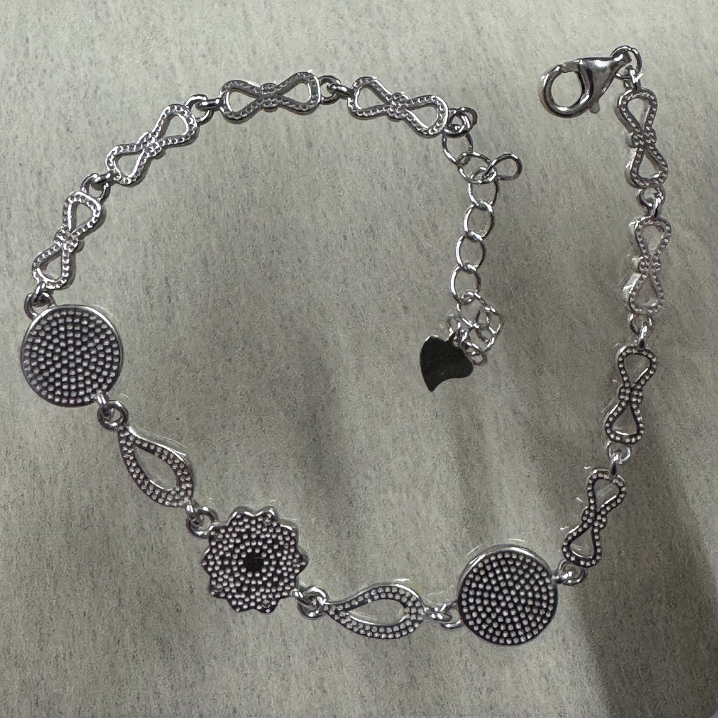 Reverse of the sterling silver bracelet, showing the granulated backs of the discs and flower and the beaded bow links.