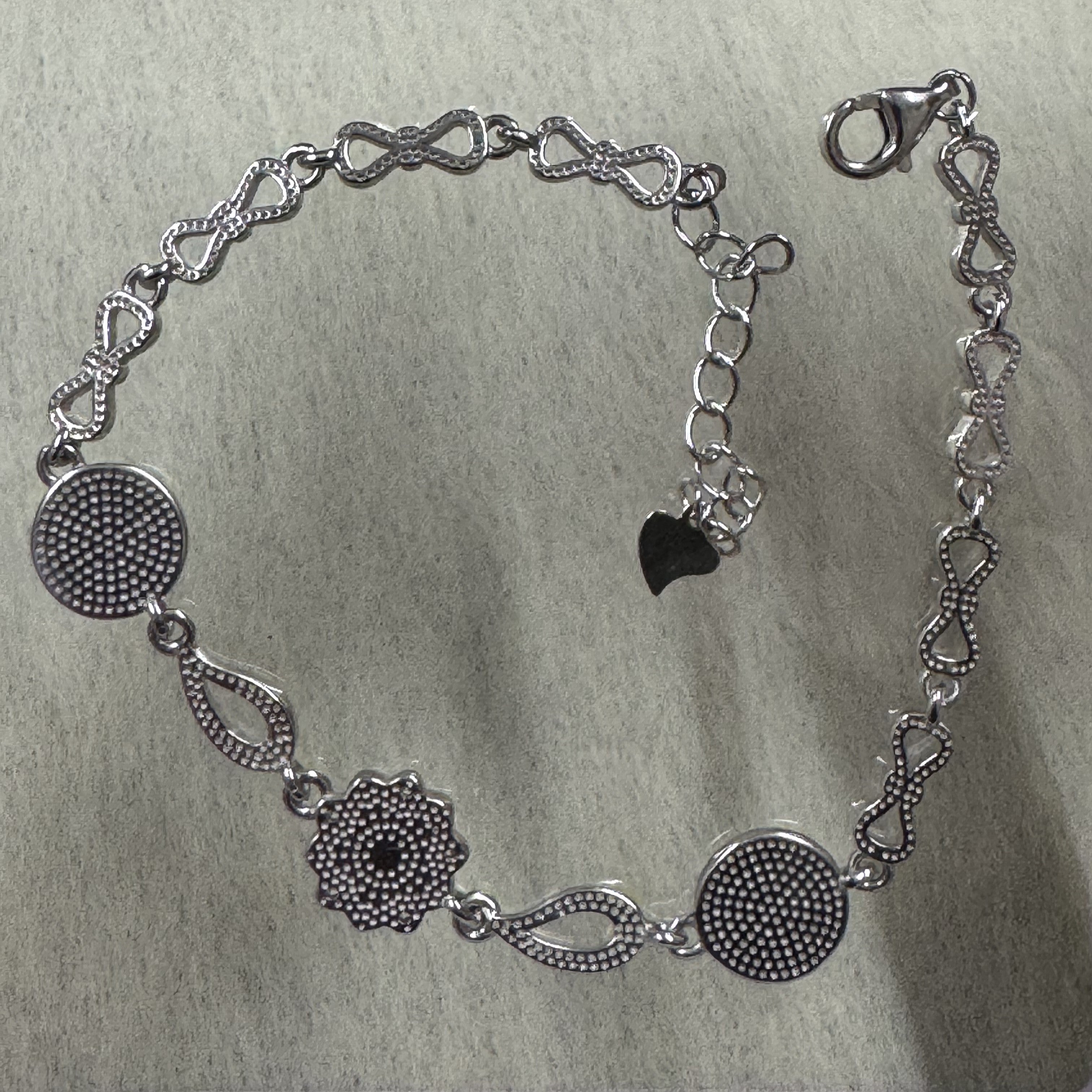 Reverse of the sterling silver bracelet, showing the granulated backs of the discs and flower and the beaded bow links.